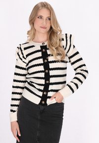 Black and white striped cardigan with textured fabric, round neckline, and button closure featuring wooden buttons and ruffled shoulder accents.