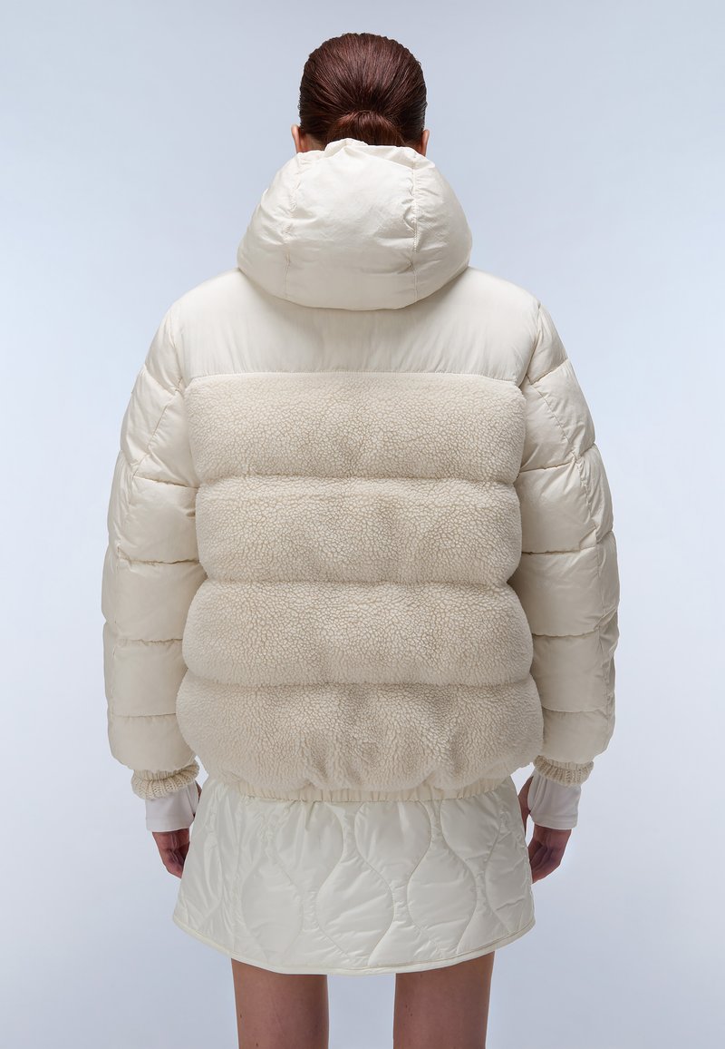 Giacca puffer beige con una sezione centrale in shearling testurizzato, cappuccio e polsini elastici. Tessuto liscio con design a cuciture orizzontali.
