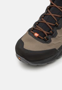 Hiking shoe featuring a dark grey and khaki textile upper, reinforced toe cap, textured black accents, and orange laces.