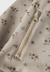 Blomsteret etui med lynlås i lyse beige stof med små brune og grønne blomster. Har en glat overflade og en robust beige lynlås.