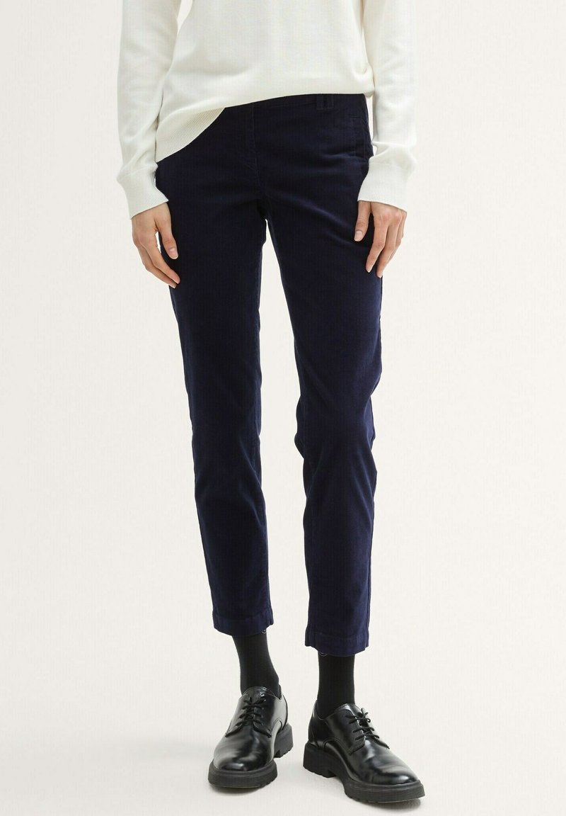 Mörkblå kordflossbyxor med avsmalnad ben, som har en knappstängning, bälteshällor och subtil textur, tillsammans med svarta läderskor.