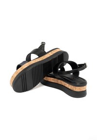 Sandales compensées en cuir noir dotées d'une semelle en liège, d'une bride réglable et d'une semelle extérieure en caoutchouc texturé pour une meilleure adhérence.