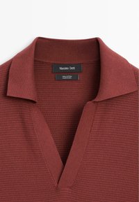 Maglione di cotone di colore rosso scuro con un motivo a maglia testurizzato e un colletto ampio e piatto con scollatura a V profonda. Etichetta visibile all'interno.