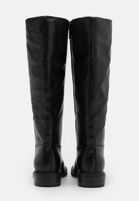 Botas de cuero negras hasta la rodilla con un acabado suave, cremalleras laterales y un tacón apilado. Detalles texturizados cerca de la parte superior y en la parte trasera.