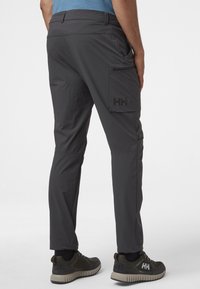 Szare techniczne spodnie o dopasowanym kroju, z kieszenią na nogawce, lekkiego materiału i z logo z tyłu. Odpowiednie do aktywności na świeżym powietrzu.