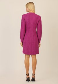 Lila Strickkleid mit langen Ärmeln, geripptem Kragen und strukturiertem Muster, das eine figurbetonte Silhouette und einen Saum über dem Knie bietet.