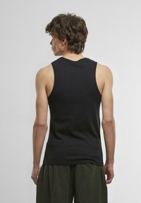 Schwarzes ärmelloses Tanktop mit einem runden Halsauschnitt, aus einem glatten Stoff gefertigt. Verfügt über eine lockere Passform und ein schlichtes Design ohne sichtbare Akzentuierungen.