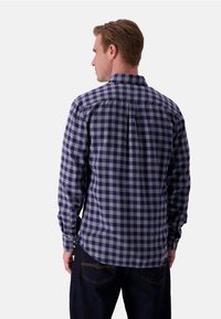 Camicia da uomo a maniche lunghe in un motivo a quadri blu navy e grigio, con polsini con bottone, colletto dritto e un orlo leggermente curvo.
