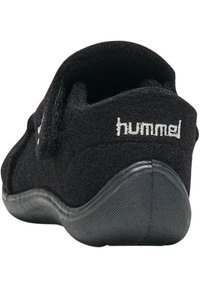 Svart filttoffel med rund form, med en strukturerad svart gummisula och vitt broderat "hummel"-logotyp på baksidan.