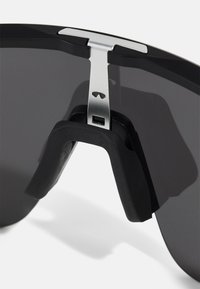 Ochelari de soare negri cu un design elegant, având o lentilă gri curbată, accente metalice și o perniță de nas din cauciuc pentru confort și stabilitate.