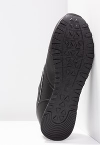 Black athletic shoe sole, rubber with textured traction patterns. Side features stitched accents and a sleek, smooth design.