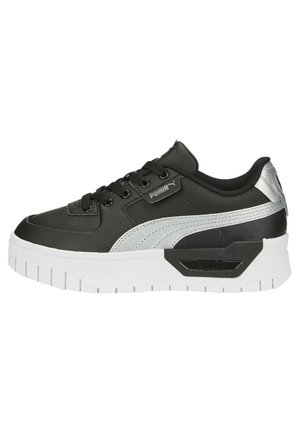 Black sneaker made of synthetic material with a white sole. Features a silver accent, lace closure, and a textured side design.