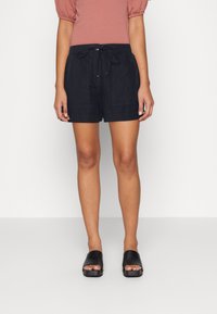 Navy linen shorts with an elastic waistband and drawstring detail, featuring side pockets and a loose fit, paired with black slide sandals.