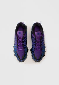 Purple and black athletic shoes with a mesh upper, curved sole design, and rubber accents; features a lacing system and branded logo.