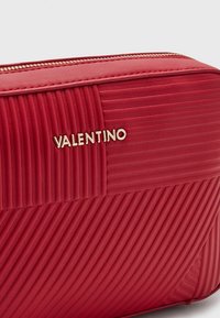 Bolso de Red Valentino con patrones de costura diagonales y verticales y un zipper dorado a lo largo del borde superior.