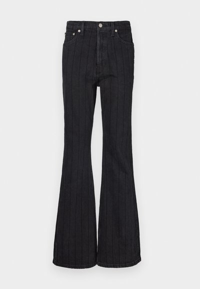 Jean flare en denim noir avec des rayures blanches verticales, cinq poches, taille haute et fermeture à bouton en métal.