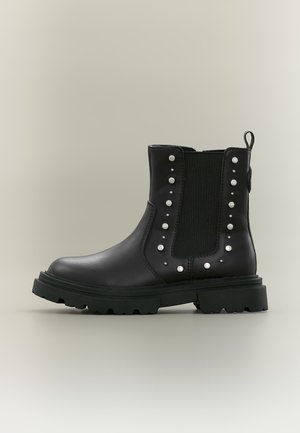 Black leather ankle boot with chunky sole, elastic side panel, and silver round studs along the sides and back pull tab.