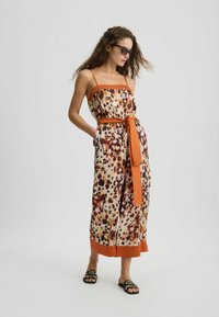 Strapless jumpsuit met oranje accent, met een luipaardprint ontwerp in warme tinten. Inclusief een bijpassende riem en zakken aan de zijkanten.