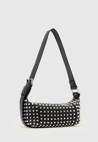Czarna skórzana torebka z srebrnymi piramidalnymi ćwiekami. Posiada szeroki pasek na ramię z regulowanym zapięciem. Prostokątny kształt i teksturowana powierzchnia.