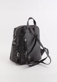 Sac à dos en cuir noir avec double fermetures éclair, poches latérales et bretelles réglables. Surface texturée avec des accents de matériel minimalistes.