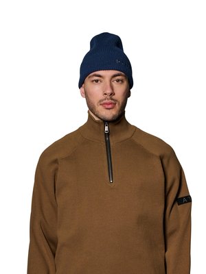 Mann trägt einen braunen Reißverschluss-Pullover und eine marineblaue gestrickte Mütze, schaut nach vorne mit neutralem Gesichtsausdruck.