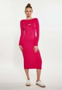 Tæt siddende, langærmet, ribbet kjole i lys pink med udskæringsdetalje ved brystet. Kombineret med hvide sneakers og lysebrune accenter.
