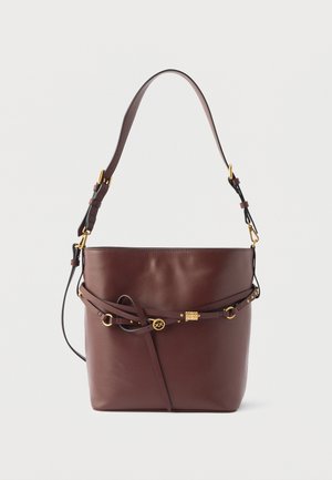 Smeđa kožna torba u obliku kante s podesivim remenom za rame i dekorativnim detaljima u zlatnoj boji, kopčom i zakovicama na prednjoj strani.