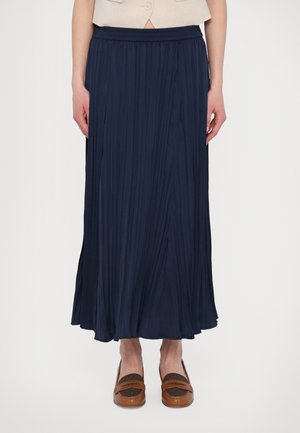 Navy pleated skirt with an elastic waistband, flowing design, and lightweight texture, paired with brown loafers featuring a textured detail.