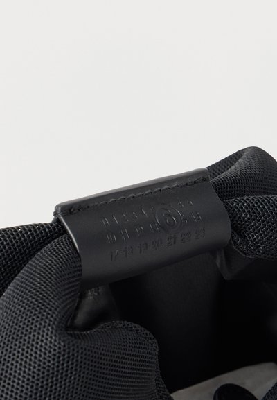 Εσωτερικό μαύρου παπουτσιού με δερμάτινη ετικέτα μεγέθους που δείχνει αριθμούς από 0 έως 23, με τον αριθμό 6 να είναι κυκλωμένος, προσαρτημένη σε επένδυση από επενδυμένο διχτυωτό ύφασμα.