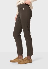 Hnedé nohavice na mieru vyrobené z elastického materiálu, s hladkou textúrou, bočnými vreckami a slim fit strihom až po členky.