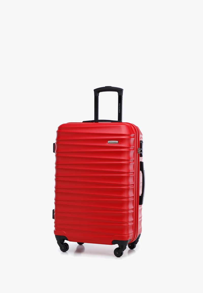 Maleta rígida de color rojo brillante con estrías horizontales, mango extensible negro y cuatro ruedas giratorias para una fácil maniobrabilidad.