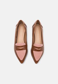 Flats en cuir marron à bout pointu, ornées d'un accent en cuir rose et d'une sangle décorative avec un petit emblème doré.