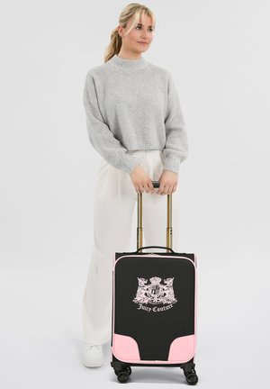 Schwarzer Koffer mit rosa Akzenten, mit einem Kronsymbol, ausziehbarem goldenen Griff und vier schwarzen Rollen für Mobilität.