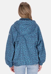 Kék leopárd mintás dzseki kapucnival, rugalmas mandzsettákkal és bő szabással. Könnyű anyagból készült, sima tapintású.