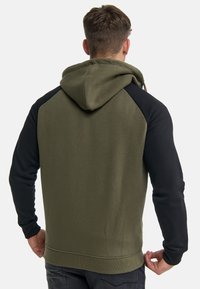 Hooded dukserica s maslinasto zelenim tijelom i crnim rukavima. Izrađena od mekanog materijala, s kenguruvim džepom i rebrastim manžetama.