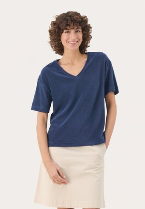 T-shirt a maniche corte blu navy con scollo a V e vestibilità comoda, abbinata a una gonna di un leggero beige. Il tessuto sembra morbido con una superficie liscia.