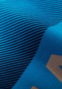 Blå textil med horisontella ränder i varierande nyanser, med en geometrisk design i en ljusare färg på ena kanten. Slät textur, tätt vävd.