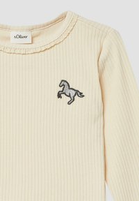 Hele beež ribikuga pikkade varrukatega pluus, millel on laineline kaelus ja hõbedaneembroidery hobuse logo rinnal.