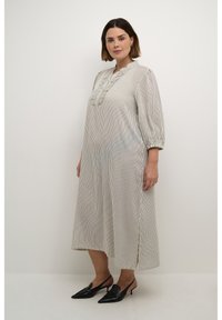 Vestido largo a rayas en tela ligera con cuello volado y mangas de tres cuartos, combinado con tacones negros de punta.