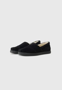 Scarpe slip-on in suede nero con punta rotonda, superficie tessurizzata, pannelli laterali elastici e una robusta suola in gomma.