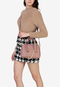 Borsa a tracolla in pelle sintetica rosa con manici doppi e accentuazione in catena dorata. La borsa presenta una forma strutturata ed è abbinata a una gonna fantasia.