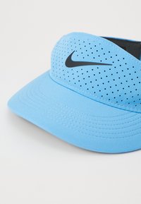 Világoskék Nike napellenző perforált szövetből, ívelt karimával és fekete Nike logóval. Texturált felület, látható varrási részletekkel.