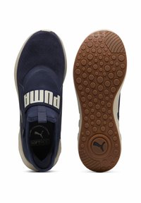 Scarpe sportive blu navy con tomaia in tessuto, fascia elastica con il marchio "PUMA" e suola in gomma testurizzata con motivi circolari.