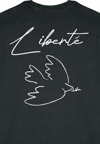 Černé tričko s bílým liniovým uměním holubice a slovem "Liberté" nad ním, obě umístěné uprostřed na zadní straně.
