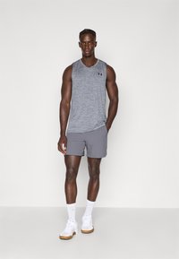 Szürke anyagú sportos tank top, melírozott textúrával, szürke sorttal párosítva. Kiegészítők: fehér edzőcipő és rövid zokni.