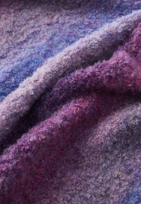 Tissu texturé dans des nuances variées de violet, présentant une surface douce et duveteuse avec un mélange de fibres claires et foncées créant de la profondeur.