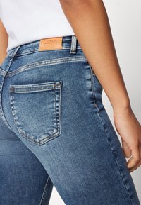 Vaqueros de mezclilla en lavado azul claro, con un bolsillo trasero con detalle de costura, una etiqueta de cuero en la cintura y un diseño de corte slim.