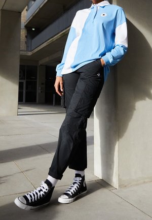 Light blue and white color-block polo shirt with long sleeves, black cargo pants, and black high-top sneakers with white laces.