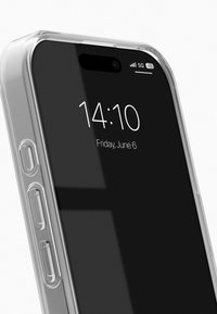 Průhledný kryt na smartphone s zaoblenými rohy, zobrazuje černou obrazovku s časem a datem. Boční tlačítka jsou viditelná; materiál působí leskle.