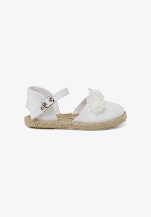 Sandale espadrille en toile blanche avec une bride réglable à la cheville, semelle en jute, et une fleur décorative en tissu blanc sur le bout.